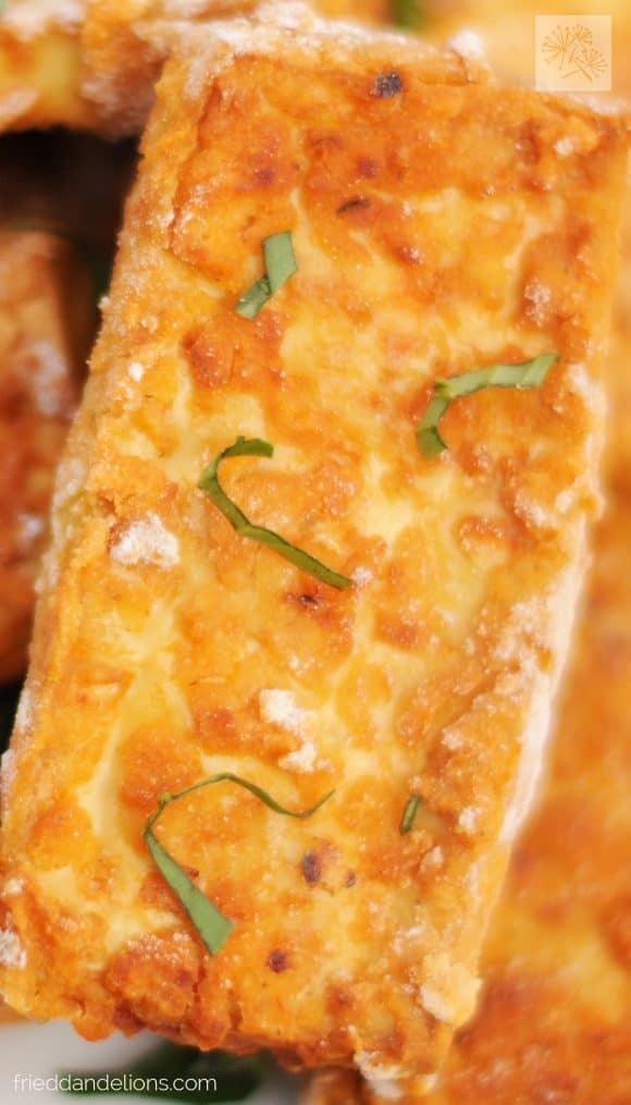 close up of crispy pizza tofu nuggets with basil garnish